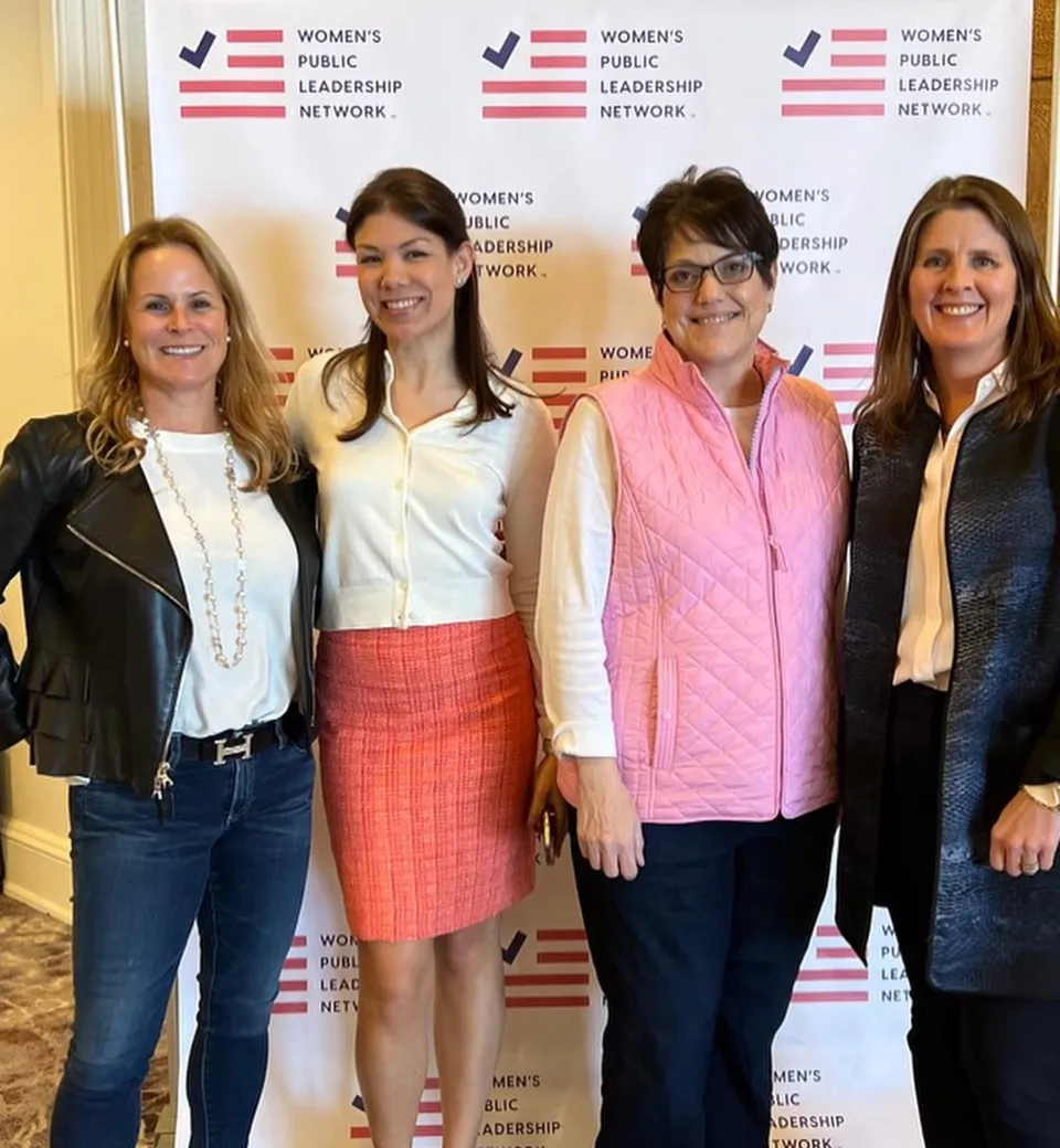 Jennifer Nassour posing with supporters in front of a Women's Public Leadership Network sign